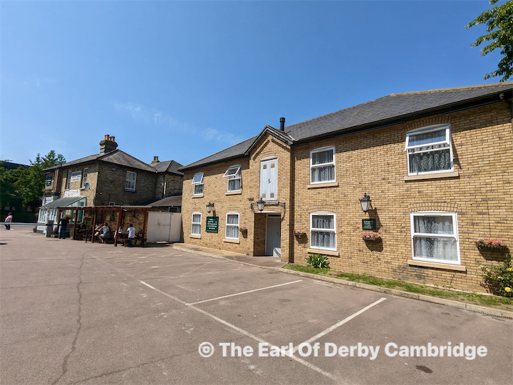 Back of a man at a concert. Hes wearing a beanie hat and a baggy denim jacket with studs. Photo with a purple hue